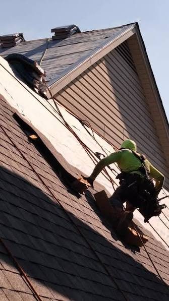 Roofer in a safety harness working a steep Ballwin MO roof during an emergency repair call