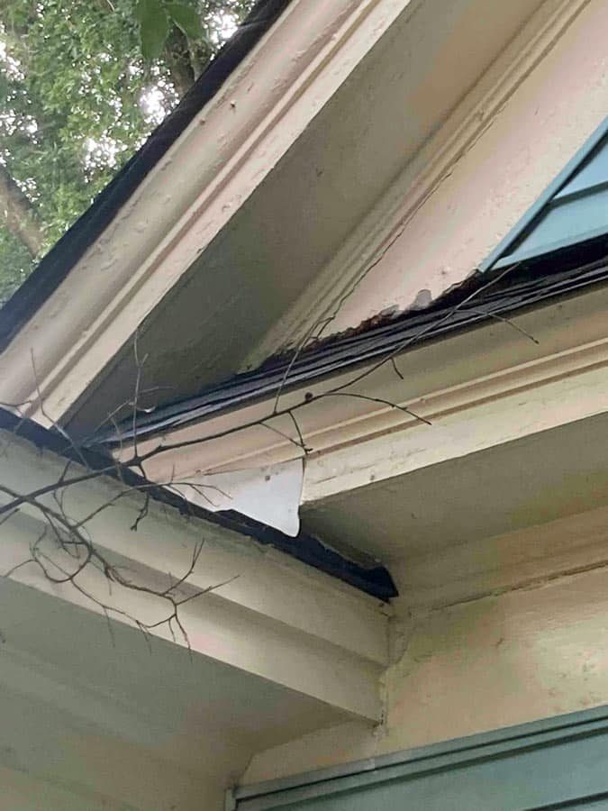 Newly installed dark seamless gutters and downspout along the roofline of a St. Louis home